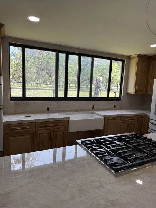 Wood cabinets and farmhouse sink under a wide window