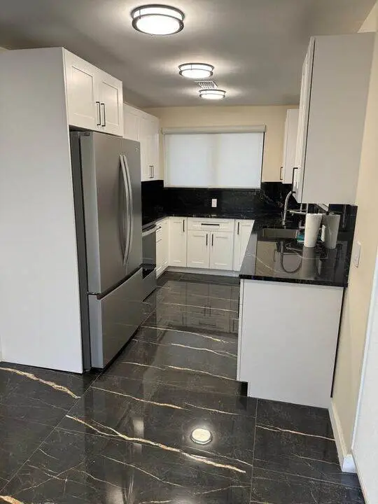White kitchen with black countertops and tile floor
